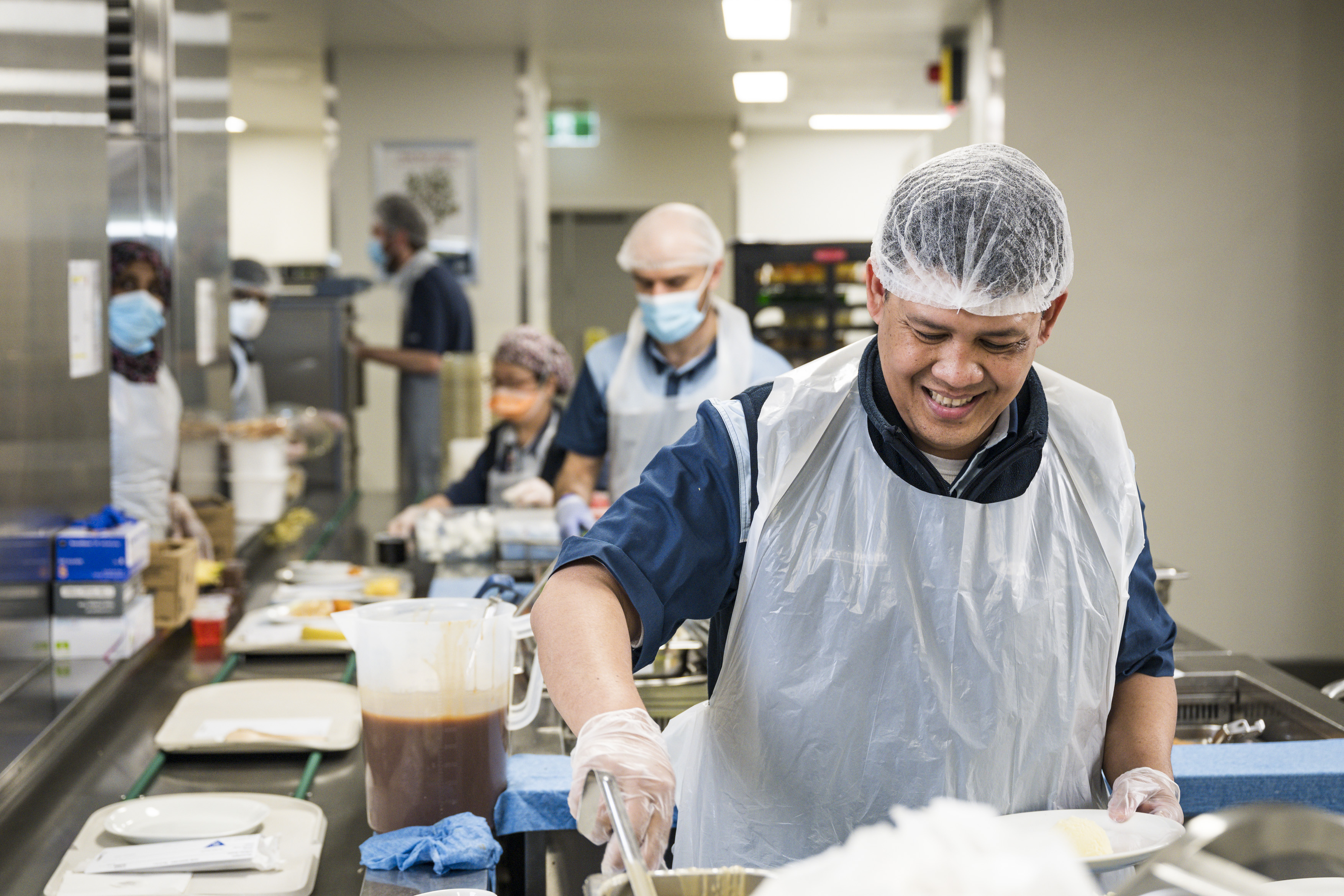 Male hospital kitchen worker preparing food for service