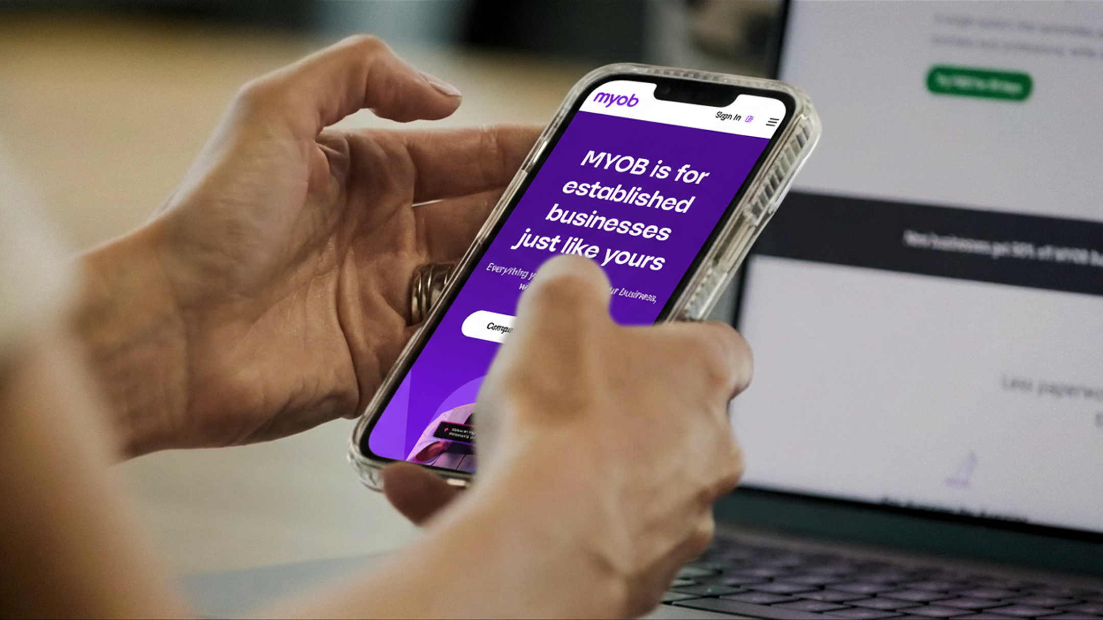 Person using a smartphone displaying the MYOB website.