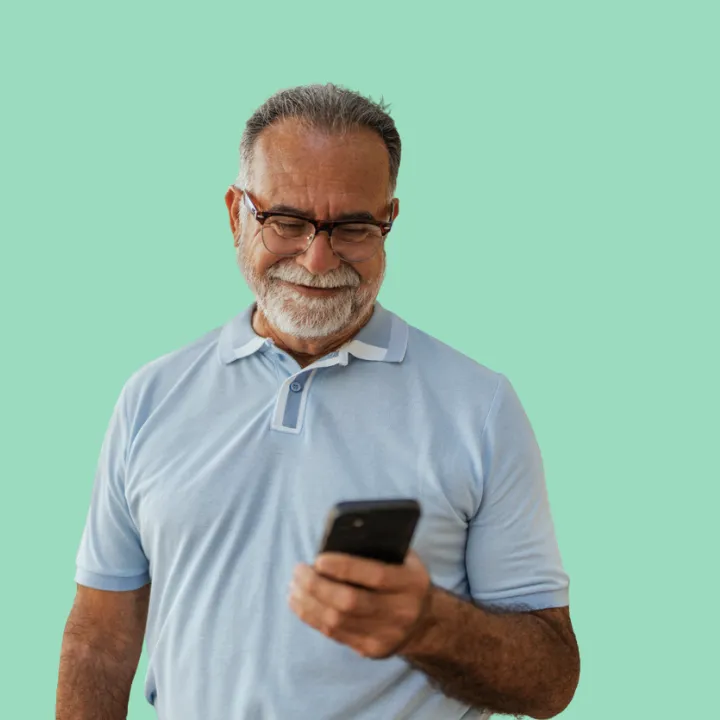A man wearing a blue shirt, smiling and looking down at his phone.