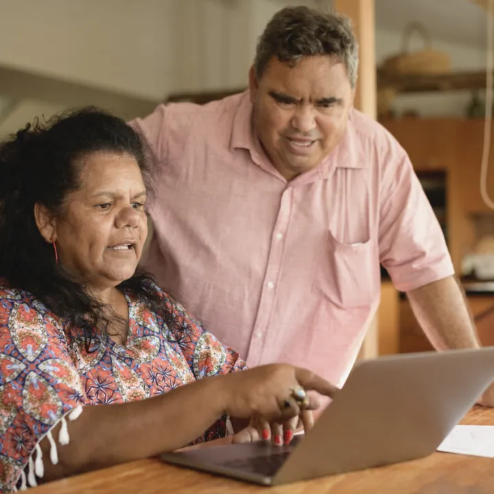 An older First Nations couple using a laptop together.