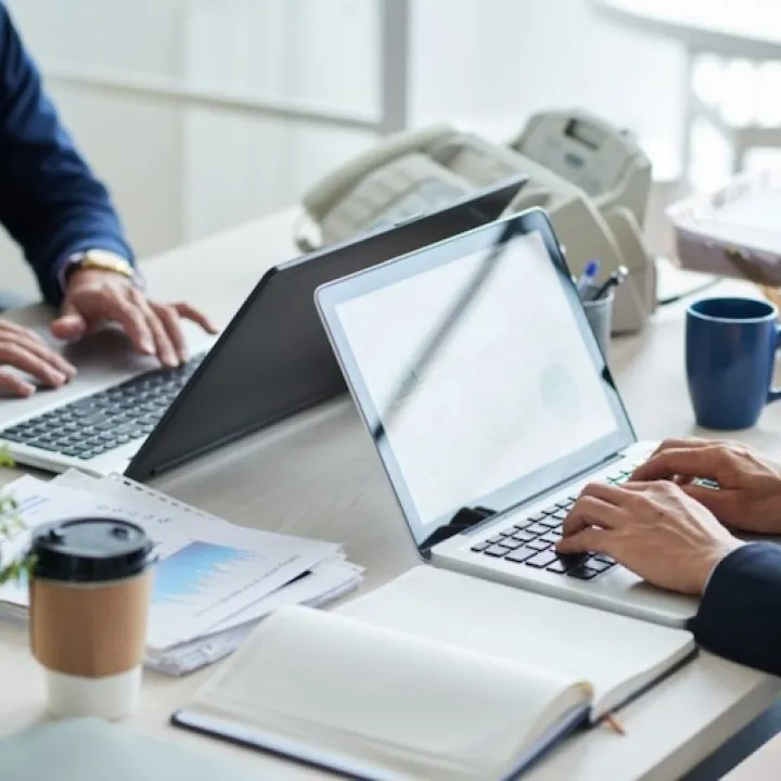Two people typing on laptops in an office