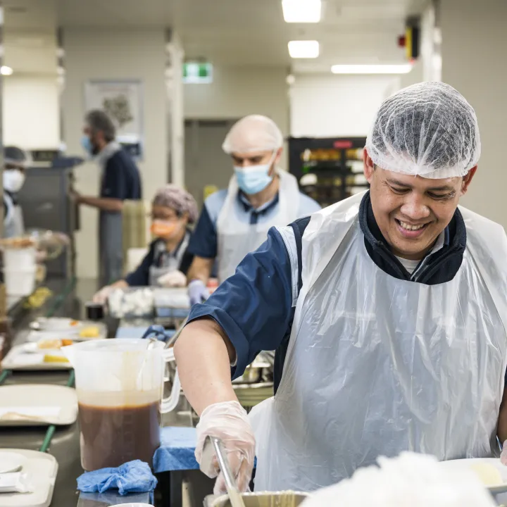 Male hospital kitchen worker preparing food for service