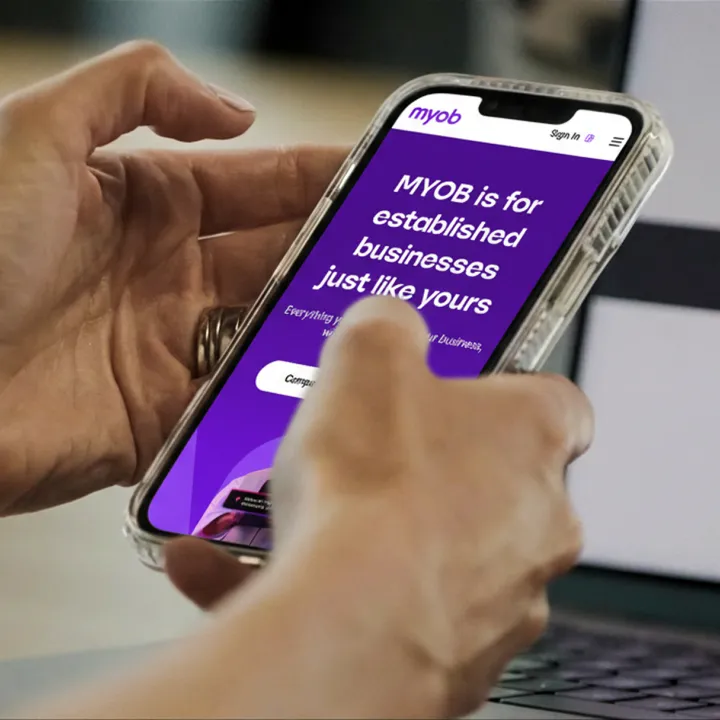 Person using a smartphone displaying the MYOB website.